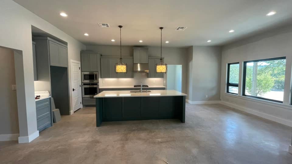 Modern open plan kitchen featuring a large central island with a dark base and stylish pendant lights, providing a spacious cooking and dining area.