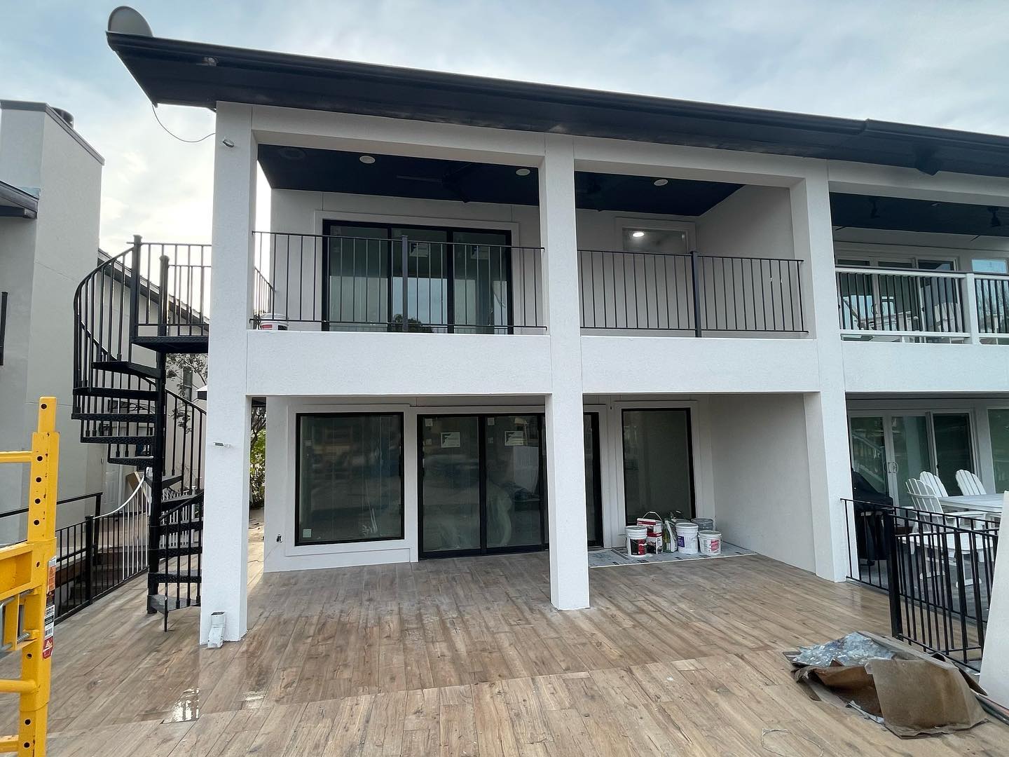 A spacious patio and balcony area with metal spiral staircases, sleek railings, and an open layout, showcasing modern design and functional outdoor space.