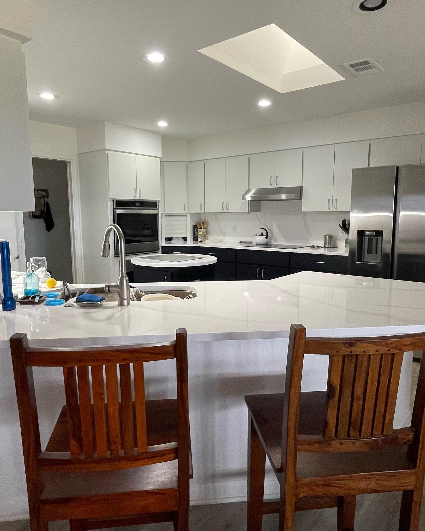 A modern kitchen interior featuring white cabinetry, an island, and stainless steel appliances.