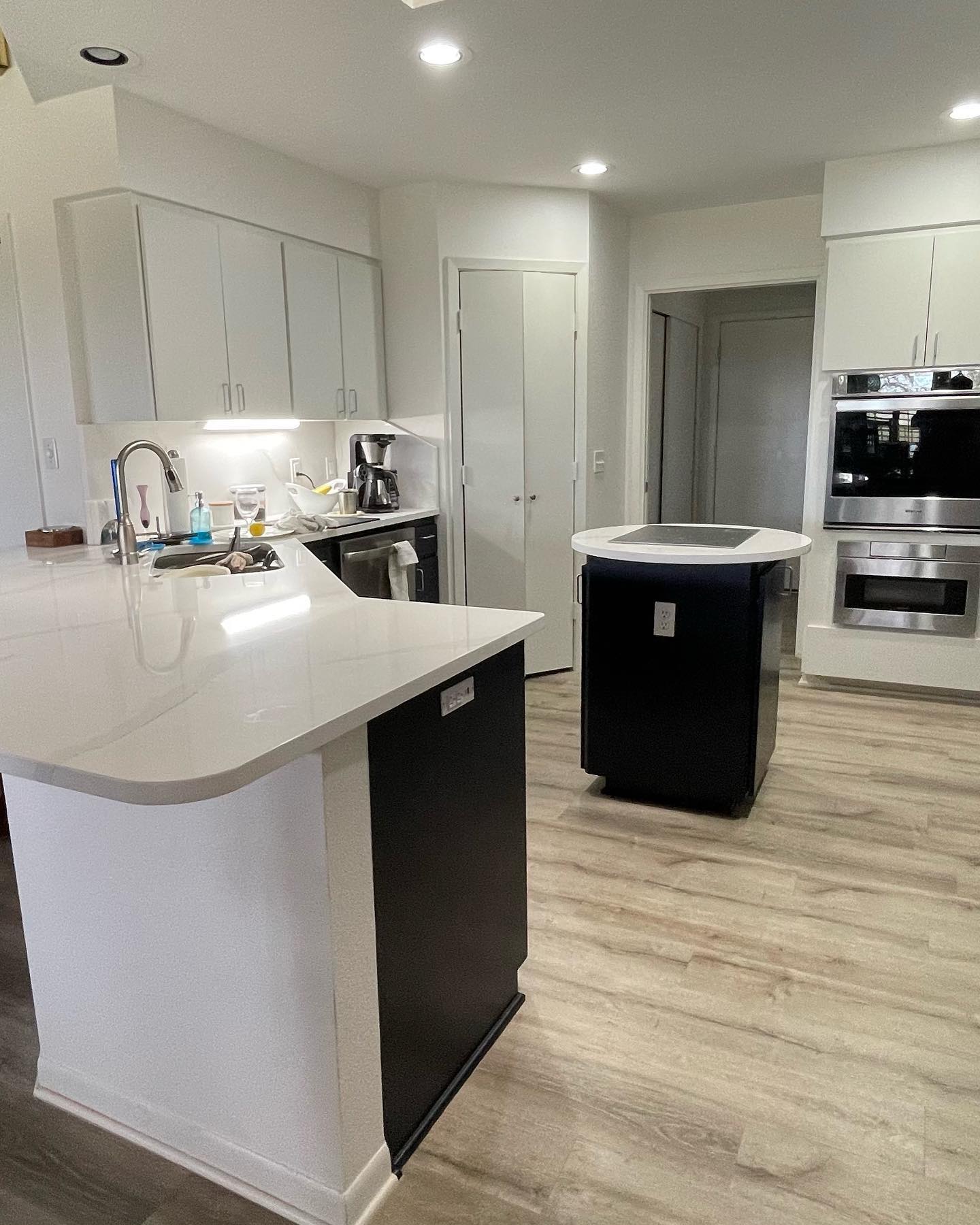 A large kitchen space with white cabinetry, black island base, modern stainless steel appliances, and ample lighting, creating an inviting and functional area.