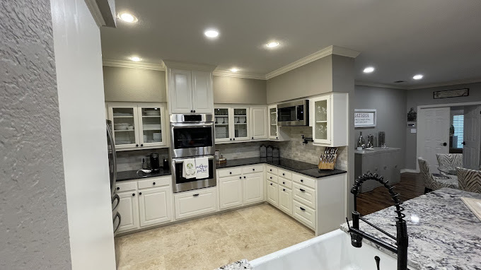 Well-equipped kitchen showcasing classic white cabinets, black granite countertops, and built-in appliances, designed for functionality and elegance.